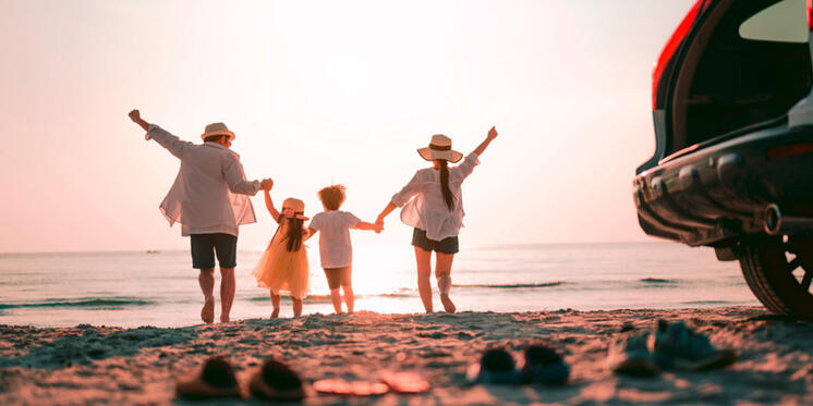 Junge Familie am Strand jubelt Richtung Meer